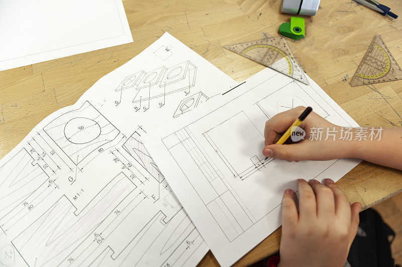 Student sitting at desk in school and drawing blueprint